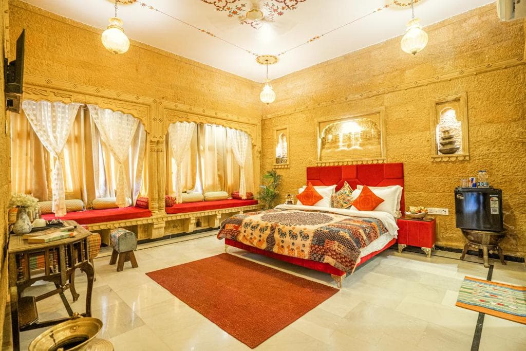 A twin-bedded room with sandstone walls and a jharokha window